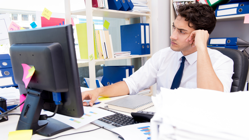 A man with ADHD sitting at a cluttered desk, struggling to concentrate on work tasks, highlighting the difficulties in meeting deadlines and managing focus (tCaPC).
