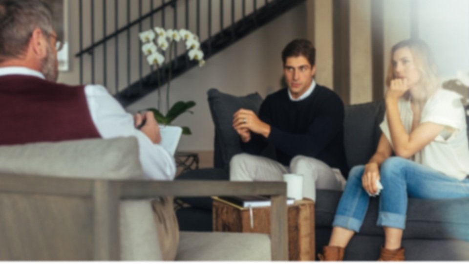 A couple sitting on a couch during a therapy session to improve their relationship (tCaPC)