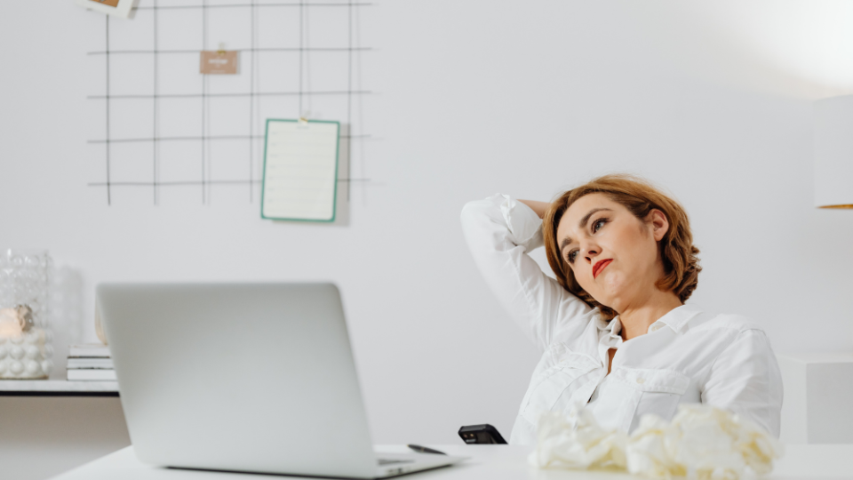 A woman at her desk, lost in thought, representing overthinking at tCaPC
