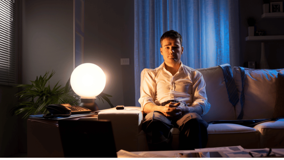 Image depicts a man alone on a couch, lost in thought. From tCaPc, symbolizing grief and loneliness.